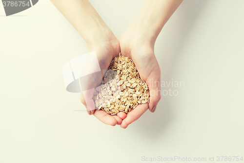 Image of close up of woman hands holding oatmeal flakes