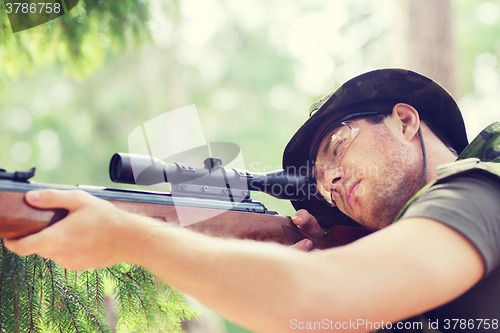 Image of young soldier or hunter with gun in forest