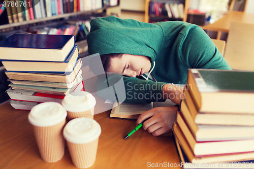 Image of tired student or man with books in library