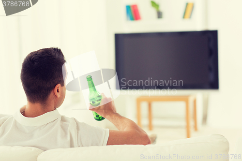 Image of man watching tv and drinking beer at home