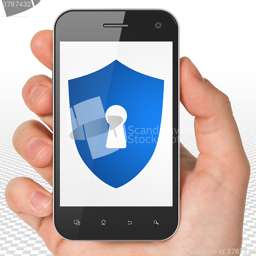 Image of Security concept: Hand Holding Smartphone with Shield With Keyhole on display