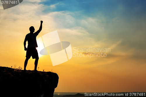 Image of Man stands near the cross on top of mountain