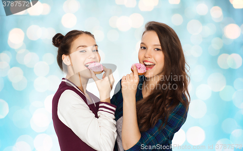 Image of happy pretty teenage girls eating donuts