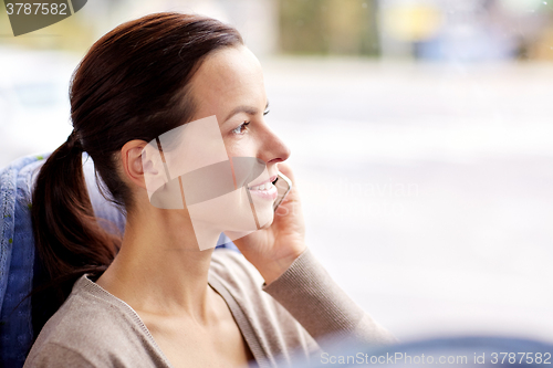 Image of happy woman in travel bus calling on smartphone