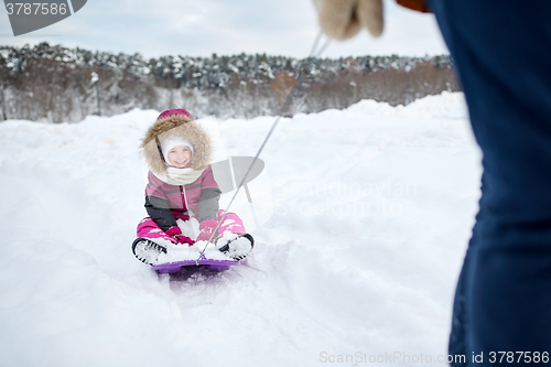 Image of parent carrying happy little kid on sled in winter