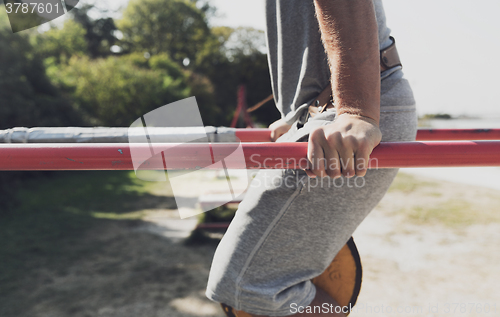 Image of young man exercising on parallel bars outdoors