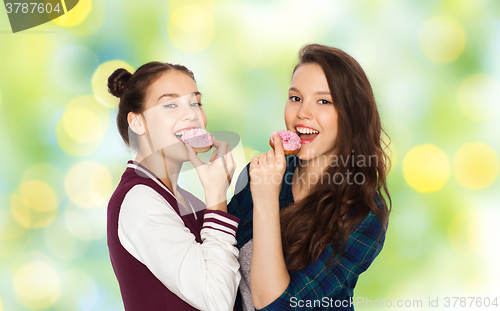 Image of happy pretty teenage girls eating donuts