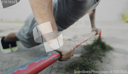 Image of young man exercising on horizontal bar outdoors