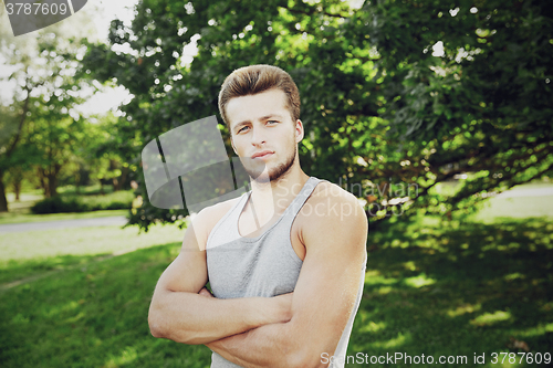 Image of sporty young man with crossed arms at summer park