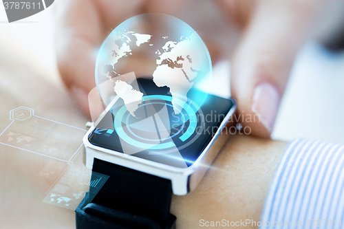 Image of close up of hand with globe hologram on smartwatch