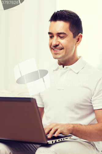 Image of happy man working with laptop computer at home