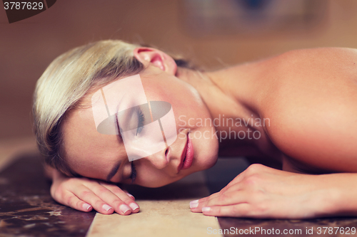 Image of young woman lying on hammam table in turkish bath