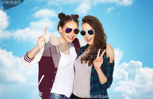 Image of smiling teenage girls in sunglasses showing peace