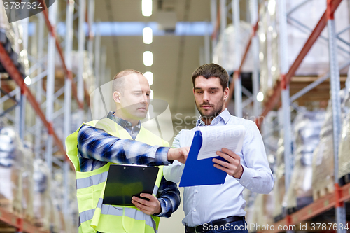 Image of worker and businessmen with clipboard at warehouse