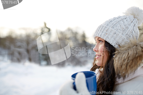 Image of happy young woman with tea cup outdoors in winter