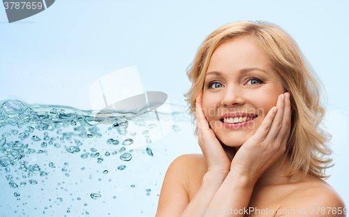 Image of smiling woman with bare shoulders touching face