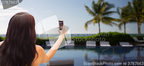 Image of young woman taking selfie with smartphone