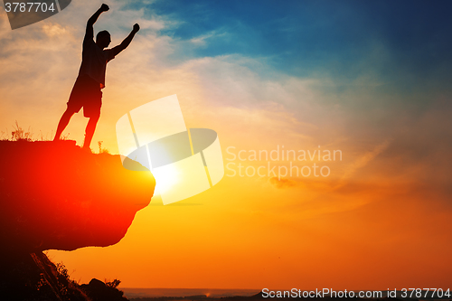 Image of Man stands near the cross on top of mountain