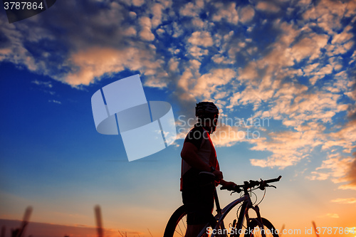 Image of Man Cyclist with bike on sunset