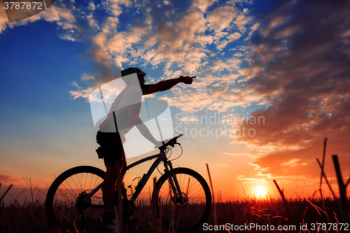 Image of Man Cyclist with bike on sunset