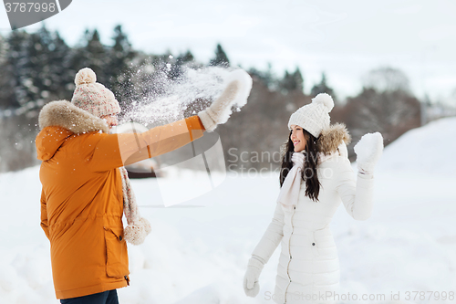 Image of happy couple playing with snow in winter