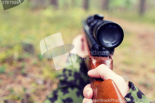 Image of close up of soldier or hunter with gun in forest