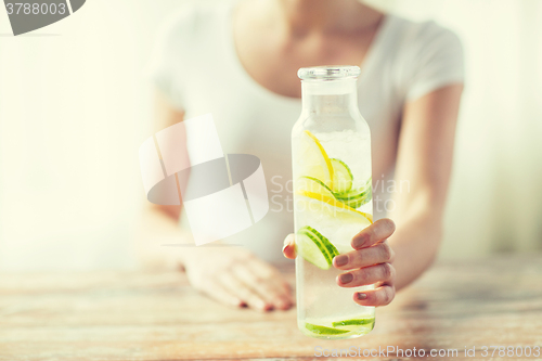 Image of close up of woman with fruit water in glass bottle