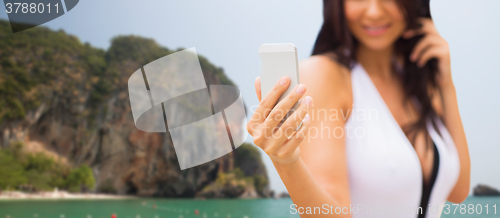 Image of young woman taking selfie with smartphone on beach