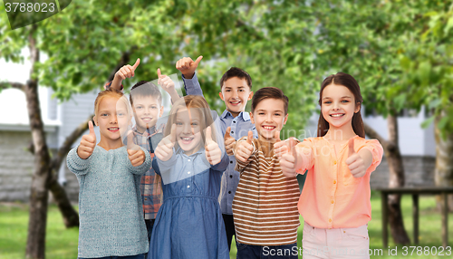 Image of happy children showing thumbs up over backyard