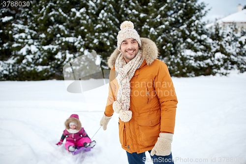 Image of happy man carrying little kid on sled in winter