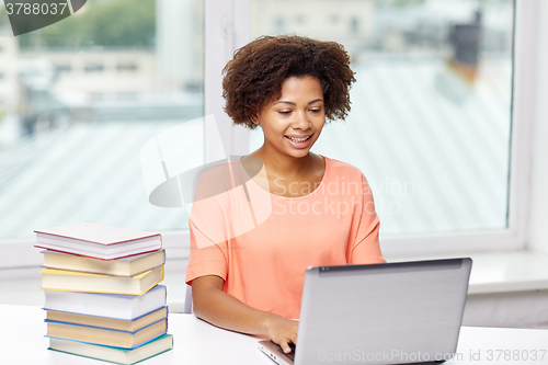 Image of happy african american woman with laptop at home