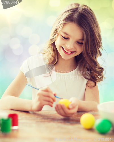 Image of happy girl with brush coloring easter eggs