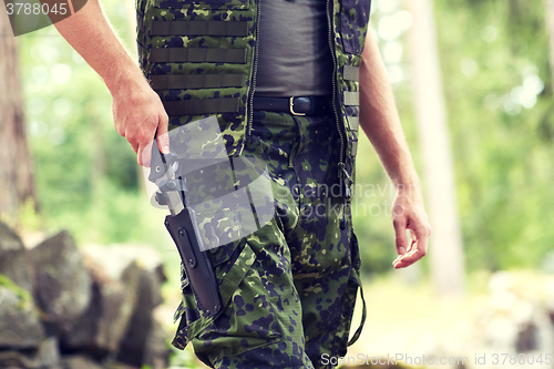 Image of close up of soldier or hunter with knife in forest