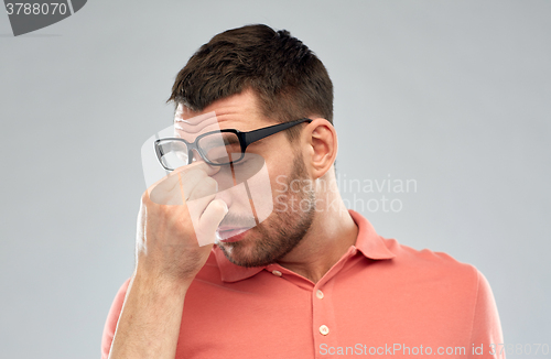 Image of tired man with eyeglasses touching nose bridge