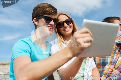 Image of group of smiling friends with tablet pc outdoors