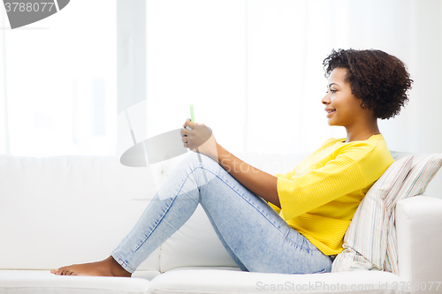 Image of happy african woman with smartphone at home