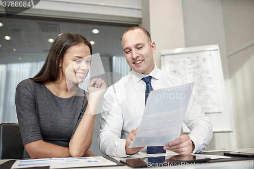 Image of smiling businesspeople with papers in office