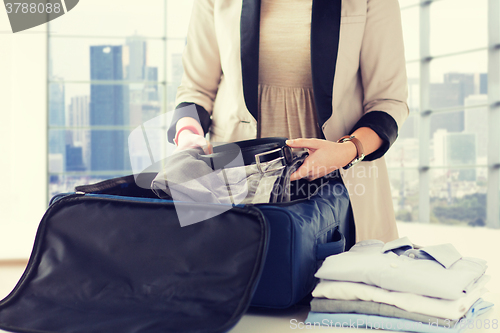 Image of woman packing formal male clothes into travel bag