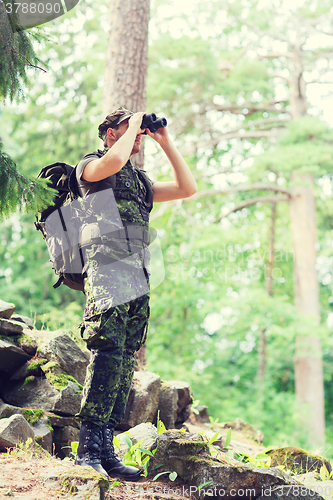 Image of soldier with binocular and backpack in forest