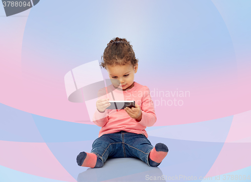 Image of smiling little baby girl playing with smartphone