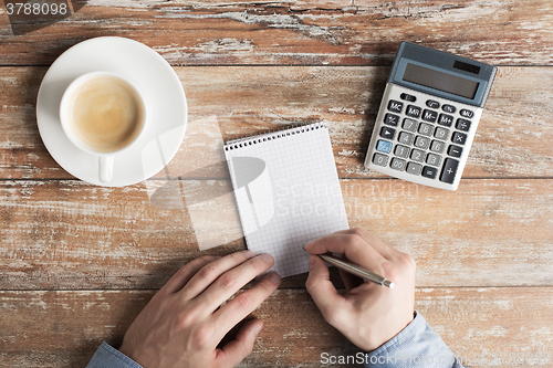 Image of close up of hands with calculator and notebook