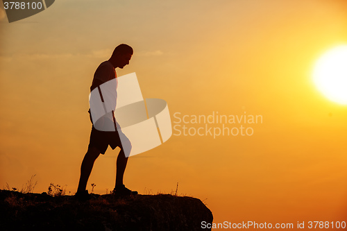 Image of Man stands near the cross on top of mountain