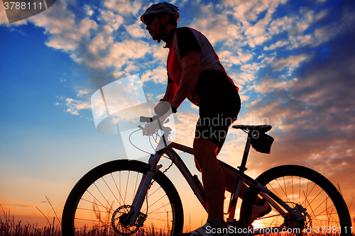 Image of Man Cyclist with bike on sunset