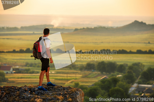 Image of Hiker with backpack standing on top of a mountain