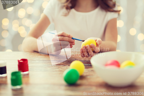 Image of close up of girl with brush coloring easter eggs