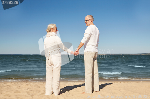 Image of happy senior couple holding hands summer beach