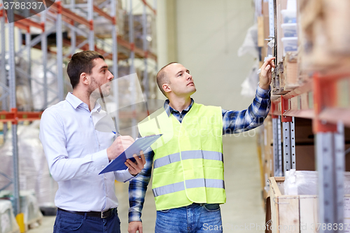 Image of worker and businessmen with clipboard at warehouse