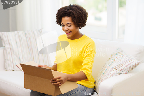 Image of happy african young woman with parcel box at home