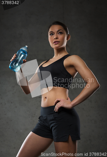 Image of woman drinking water from bottle in gym