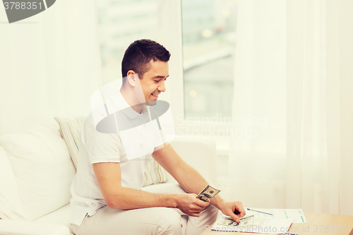 Image of man with papers and calculator at home